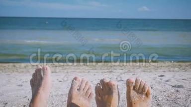 男人和女人`脚在沙滩上靠在大海上嬉戏，有趣地扭动手指。 恋爱中的情侣。 浪漫
